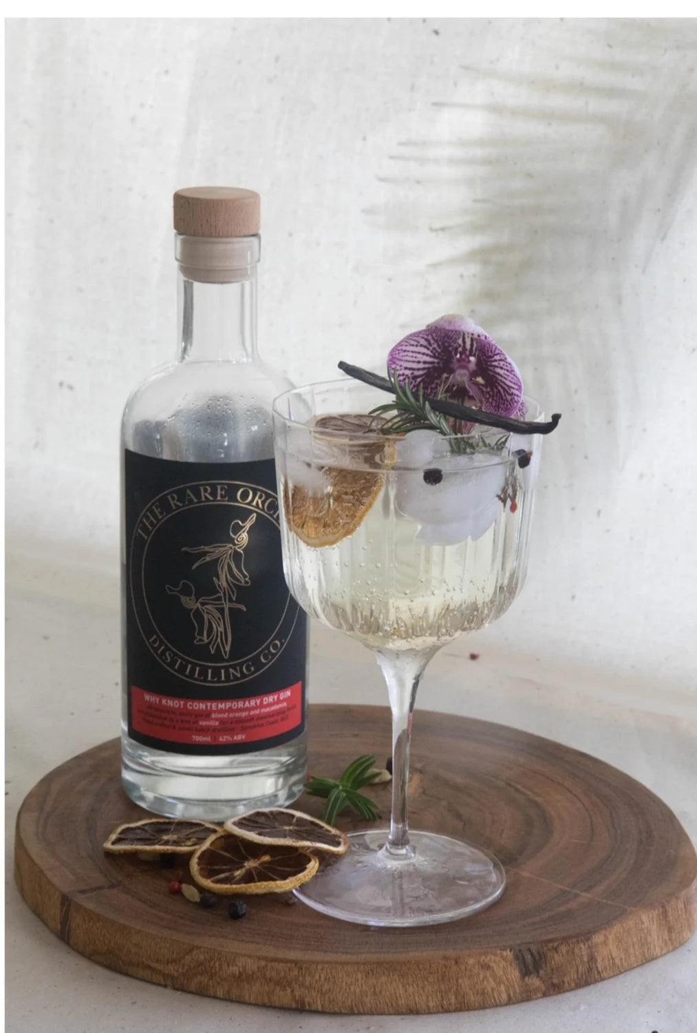 WHY KNOT Contemporary Dry Gin, real bottle beside a garnished gin and tonic with orchid